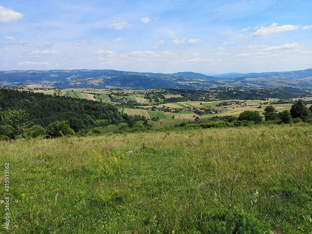 Rolling hills with grassy field and villages and agricultural fields in the background