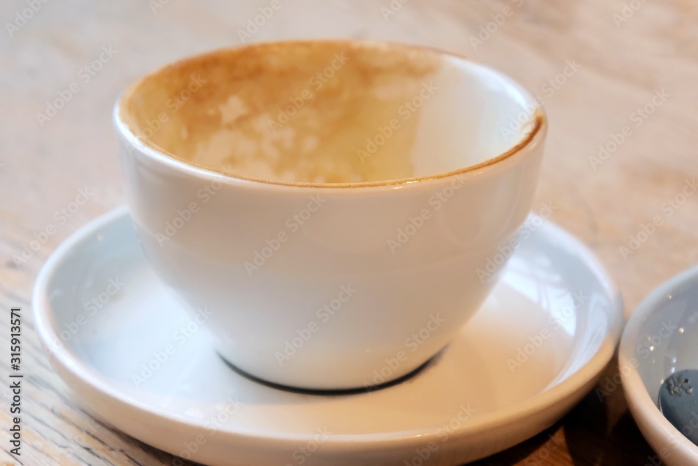 empty and dirty cups of coffee after breakfast. Dirty coffee cups with milk foam. Mess on the table after breakfast with dirty mug. Afterparty. White porcelain cup with leftover cappuccino. empty and dirty cups of coffee after breakfast. Dirty coffee cups with milk foam. Mess on the table after breakfast with dirty mug. Afterparty. White porcelain cup with leftover cappuccino.