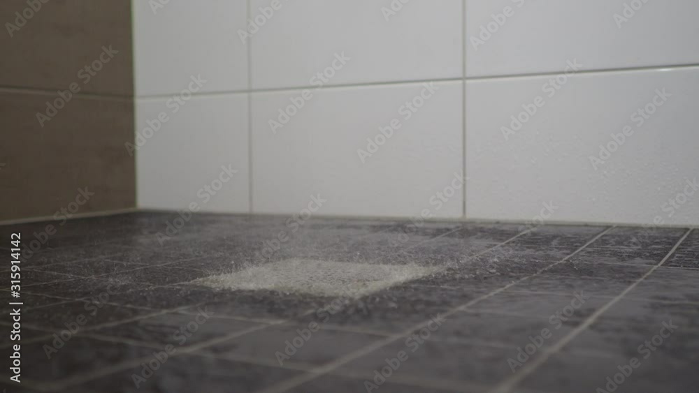 Water from the rain shower, slowly running down into a bathroom floor