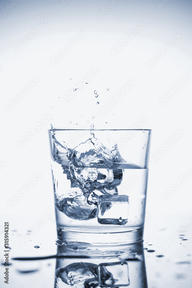 Clear mineral water splashes in a glass with ice. Clear mineral water splashes in a glass with ice.