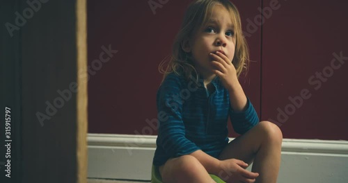 Thoughtful toddler using his potty at home