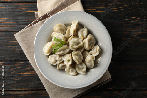 Towel and plate with dumplings on wooden background, top view