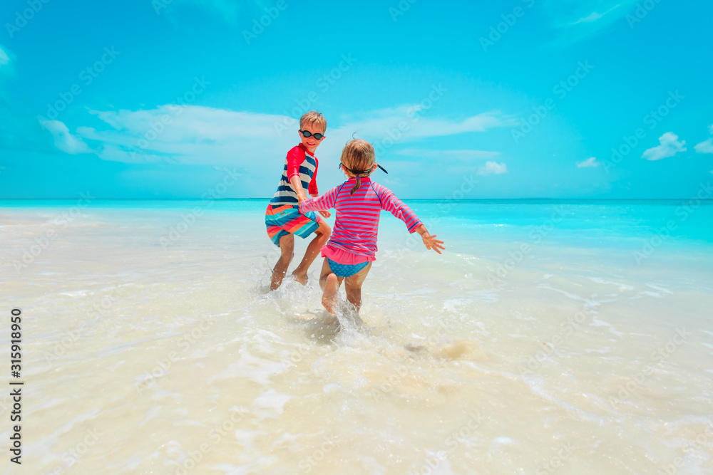 little girl and boy run play with water on beach little girl and boy run play with water on beach