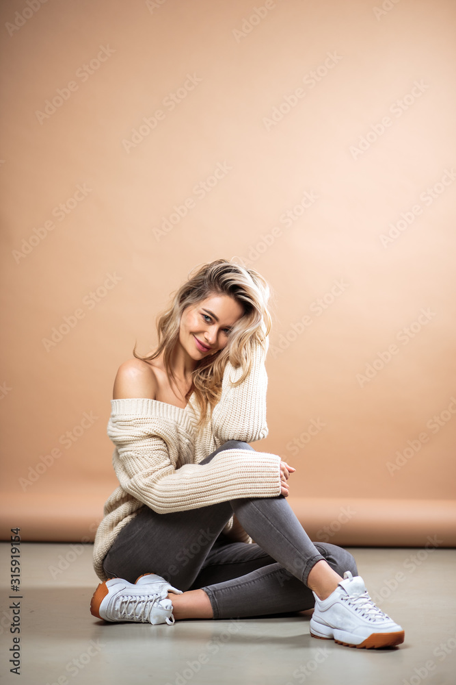 Beautiful blonde woman in a knitted sweater over brown background. Casual style, fashion beauty portrait Beautiful blonde woman in a knitted sweater over brown background. Casual style, fashion beauty portrait
