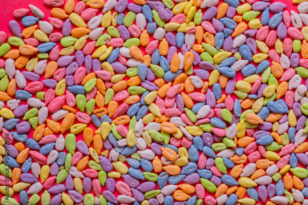 Sunflower seeds in colored glaze lie on a pink background. Flat lay, copy space, top view. Sunflower seeds in colored glaze lie on a pink background. Flat lay, copy space, top view.