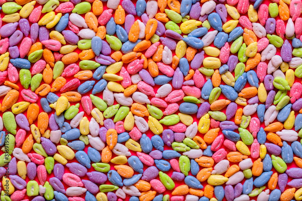 Sunflower seeds in colored glaze lie on a pink background. Flat lay, copy space, top view. Sunflower seeds in colored glaze lie on a pink background. Flat lay, copy space, top view.