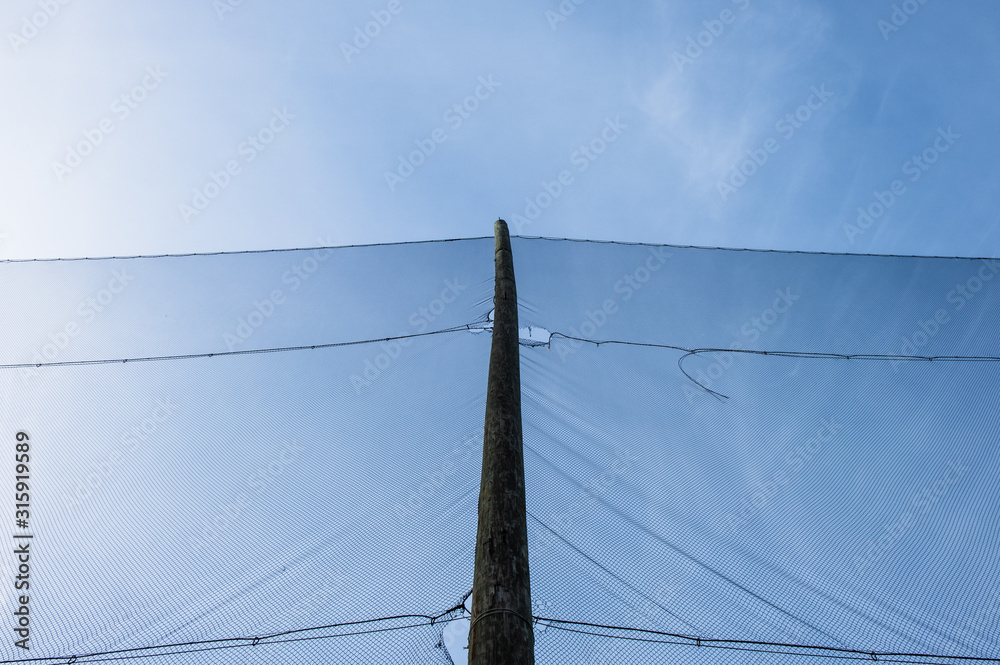 Fototapeta premium Outdoor golf range netting. Looking up at pole with black netting. 