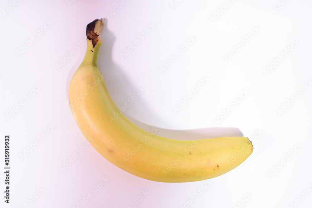 One yellow tasty healthy banana close-up on a white background. One yellow tasty healthy banana close-up on a white background.
