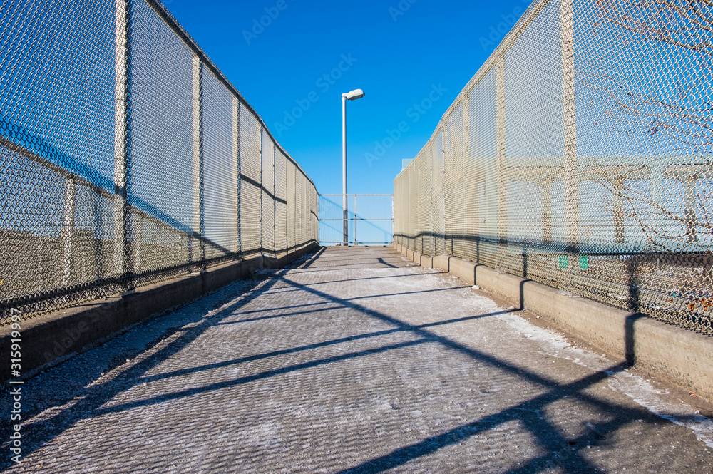 Outdoor overpass ramp walkway with chain link fence. Industrial design and detail.