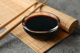 Bowl of soy sauce on gray background, space for text. Closeup