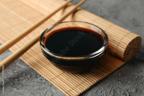 Bowl of soy sauce on gray background, space for text. Closeup photo