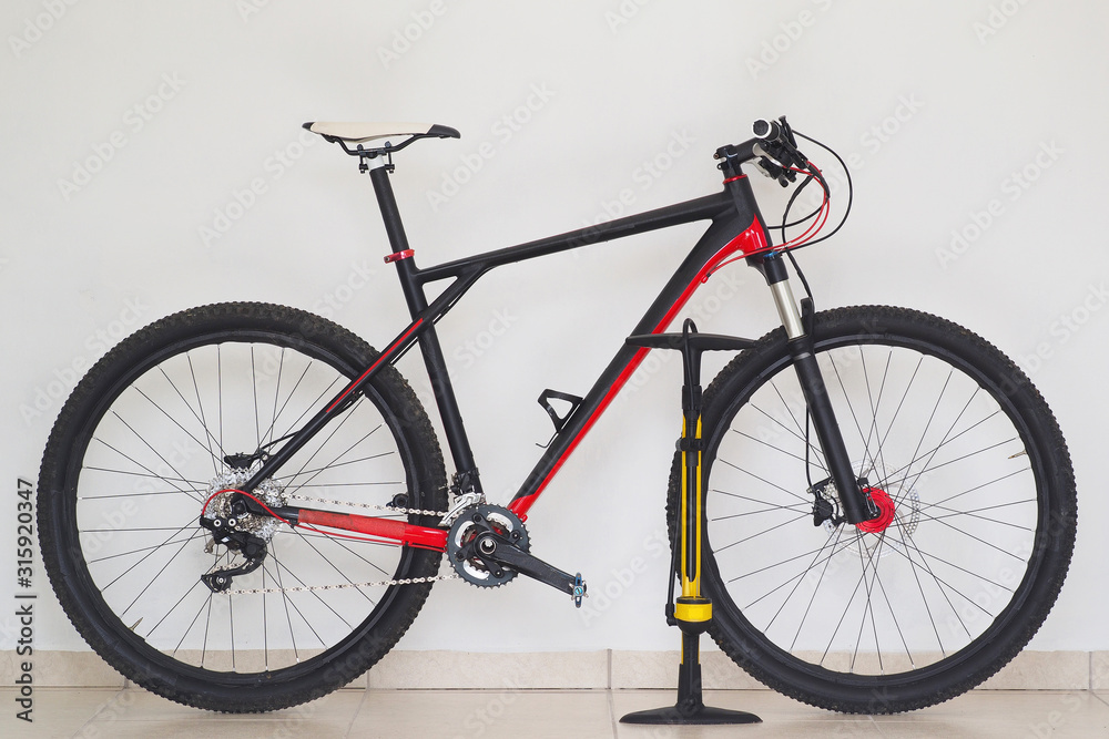 Lifestyles. Cross country mountain bike at home with yellow pump, white wall background. Lifestyles. Cross country mountain bike at home with yellow pump, white wall background.