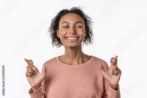 Obraz na plátne African american woman over isolated white background with fingers crossing