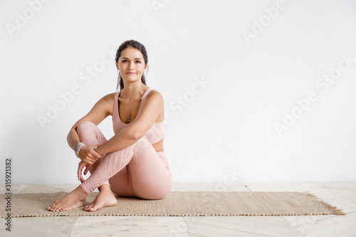 Canvas Print Attractive happy young asian yogi woman working out indoors in white cozy sport class