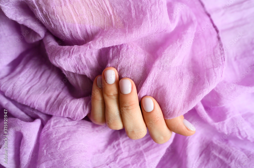 a woman's hand with pale lilac nails and lilac cotton fabric a woman's hand with pale lilac nails and lilac cotton fabric