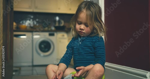 Little toddler sitting on potty at home and pulling his underpants