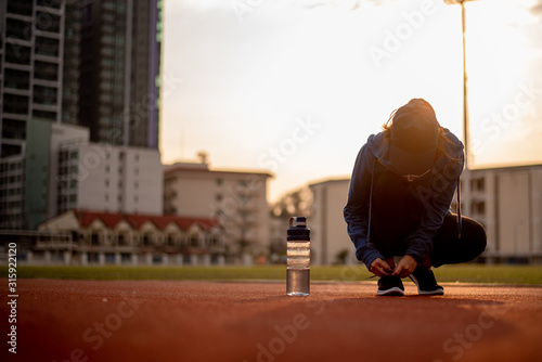 Beautiful female athletes tie shoelaces on sneakers. Beautiful female athletes are sitting on a shoelace on a black sneakers. Healthy lifestyle concepts