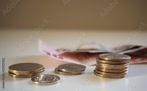 Coins in first perspective with red banknotes behind, of the currency turkish lira, fading neutral background