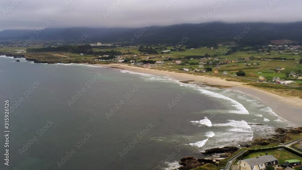 Waves washing the sandy beach during the foggy day. Aerial panorama of the Playa de Arealonga, Barreiros, Galicia, Spain Waves washing the sandy beach during the foggy day. Aerial panorama of the Playa de Arealonga, Barreiros, Galicia, Spain