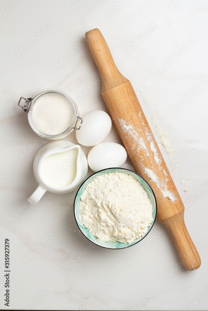 flour, eggs milk and sugar on a white background flour, eggs milk and sugar on a white background