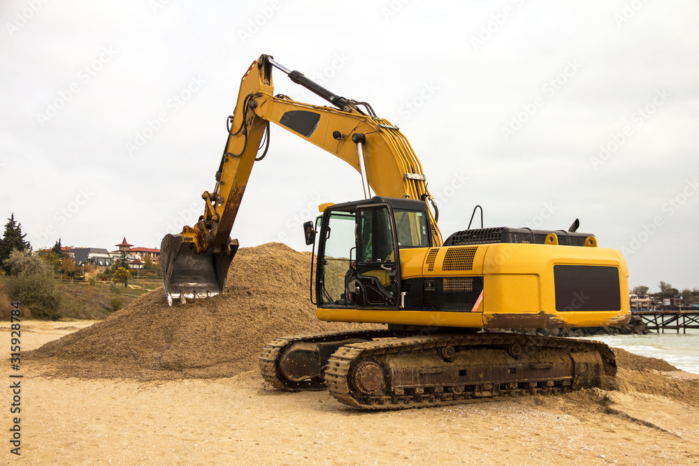 Excavator digs sand on the beach of the Bulgarian sea coast. Excavator digs sand on the beach of the Bulgarian sea coast.