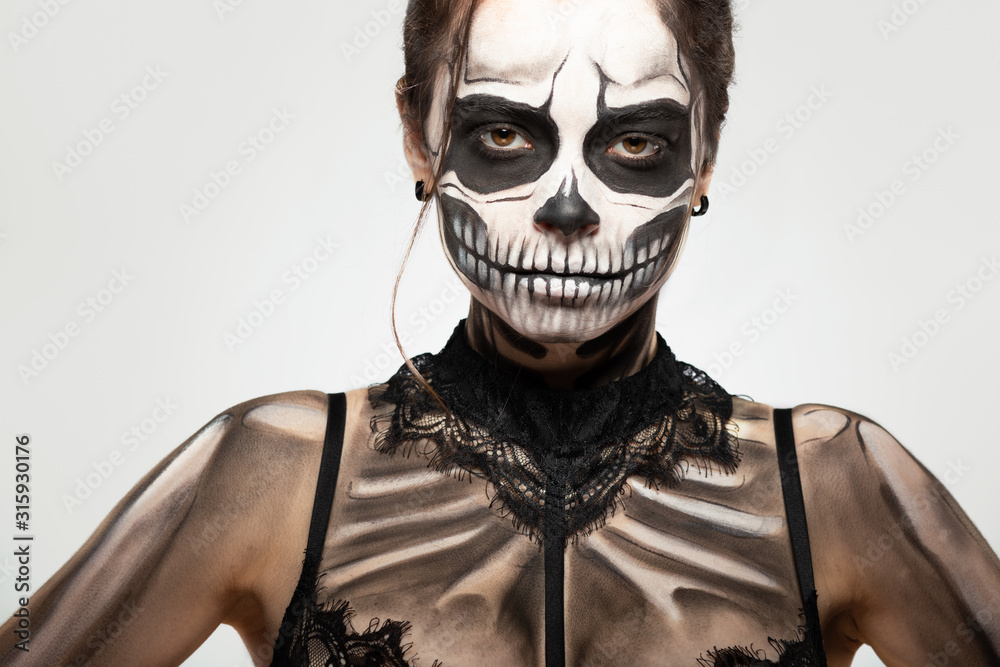 brunette girl with skull makeup for halloween on a black background - obrazy, fototapety, plakaty 
