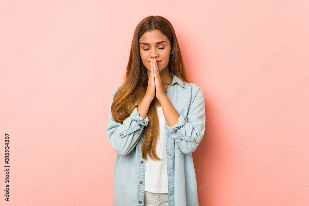 Young slim woman holding hands in pray near mouth, feels confident. Young slim woman holding hands in pray near mouth, feels confident.