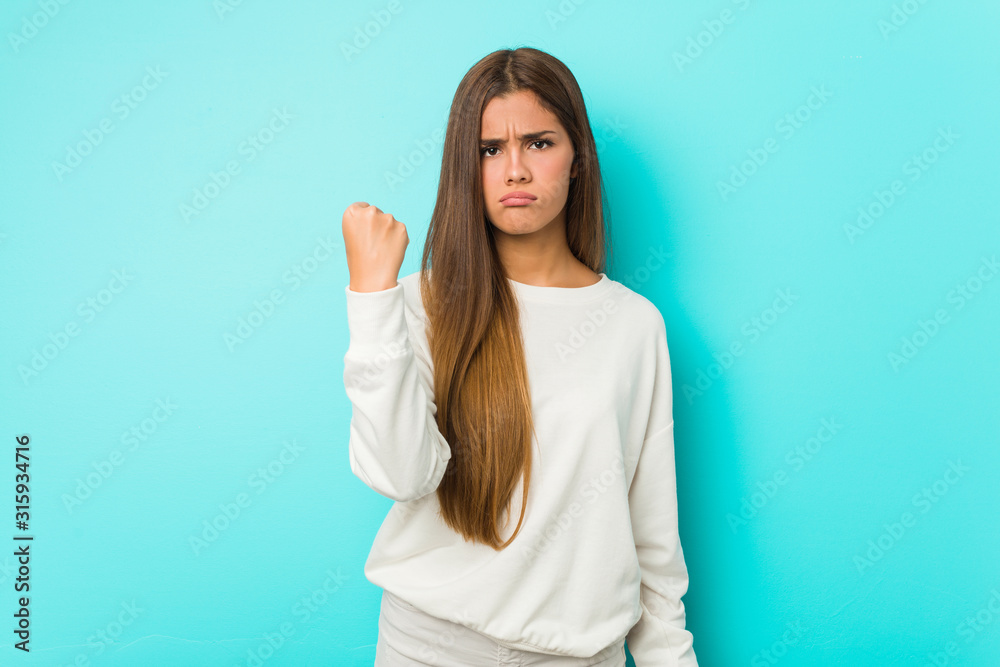 Young slim woman showing fist to camera, aggressive facial expression. Young slim woman showing fist to camera, aggressive facial expression.