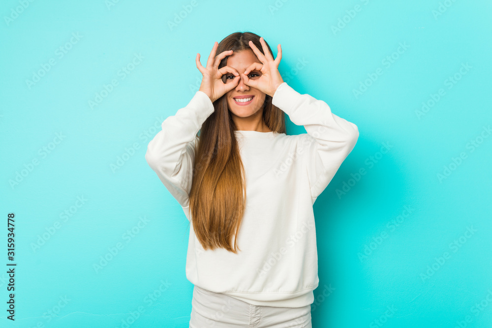 Fototapeta premium Young slim woman showing okay sign over eyes