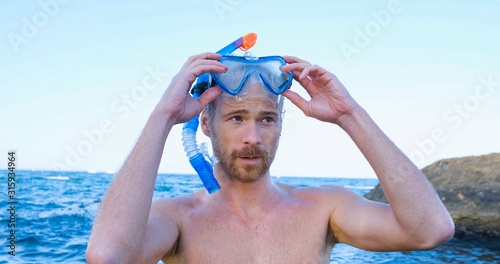 Young male swimmer with snorkling glasses dive in the summer sea 