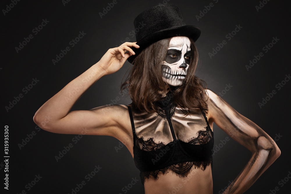 brunette girl with skull makeup for halloween on a black background