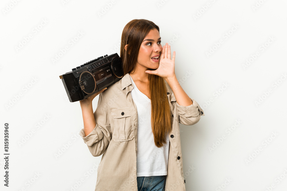 Young caucasian woman holding a guetto blaster shouting and holding palm near opened mouth.