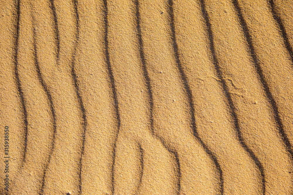 Sand on the beach forms strucktures and shapes on golden yellow fine sand background pattern holiday season summer travel vacation abstract line lines wave wavy Sand on the beach forms strucktures and shapes on golden yellow fine sand background pattern holiday season summer travel vacation abstract line lines wave wavy