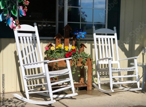 Rustic, country style front porch seating with white rocking chairs and fresh flowers