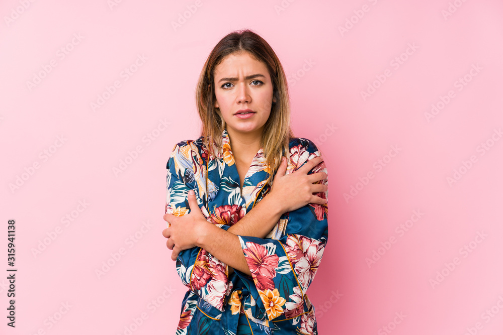 Young caucasian woman wearing pajamas going cold due to low temperature or a sickness. Young caucasian woman wearing pajamas going cold due to low temperature or a sickness.