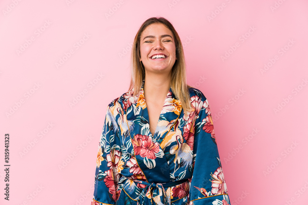 Young caucasian woman wearing pajamas laughs and closes eyes, feels relaxed and happy. Young caucasian woman wearing pajamas laughs and closes eyes, feels relaxed and happy.