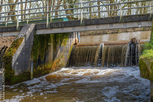 Water flows over the weir under a bridge