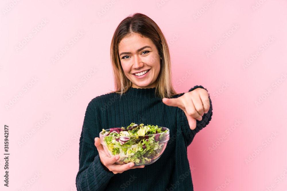 Young caucasian woman holding a salad isolated cheerful smiles pointing to front. Young caucasian woman holding a salad isolated cheerful smiles pointing to front.