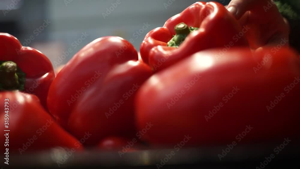 The girl buys peppers in the store. The girl chooses peppers in the store. A beautiful girl buys vegetables in a grocery store. Shopping.