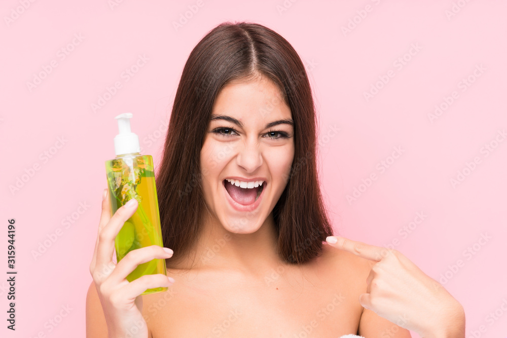 Young caucasian woman holding a moisturizer with aloe vera isolated surprised pointing at himself, smiling broadly. Young caucasian woman holding a moisturizer with aloe vera isolated surprised pointing at himself, smiling broadly.