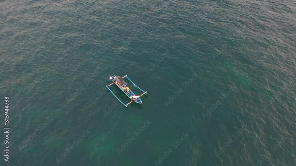 Surfers with surfing boards sailing in the traditional Balinese boat. Aerial drone high angle shot with copy space Surfers with surfing boards sailing in the traditional Balinese boat. Aerial drone high angle shot with copy space