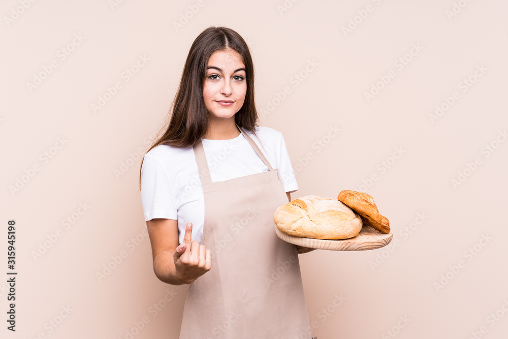Young caucasian baker woman isolated pointing with finger at you as if inviting come closer. Young caucasian baker woman isolated pointing with finger at you as if inviting come closer.