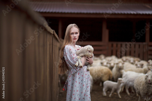 girl in the arms of a lamb farm in the mountains