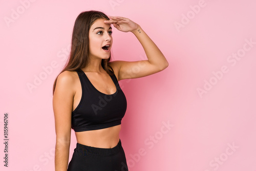 Young caucasian fitness woman doing sport isolated looking far away keeping hand on forehead.