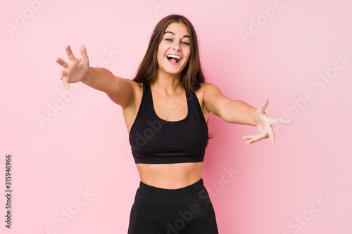 Young caucasian fitness woman doing sport isolated feels confident giving a hug to the camera.