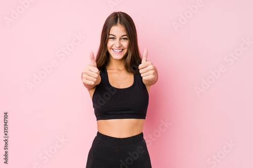 Young caucasian fitness woman doing sport isolated with thumbs ups  cheers about something  support and respect concept.