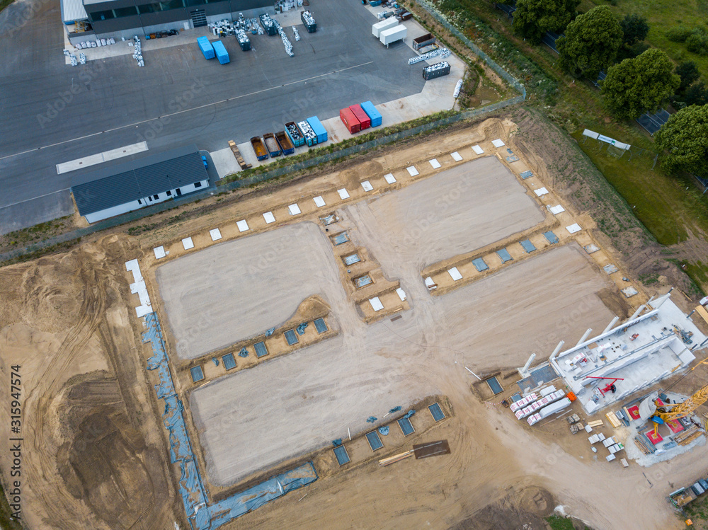 Drone photos of a large construction site on which a factory building is being erected. The foundations for the piers have been laid and and the first piers have been erected Drone photos of a large construction site on which a factory building is being erected. The foundations for the piers have been laid and and the first piers have been erected