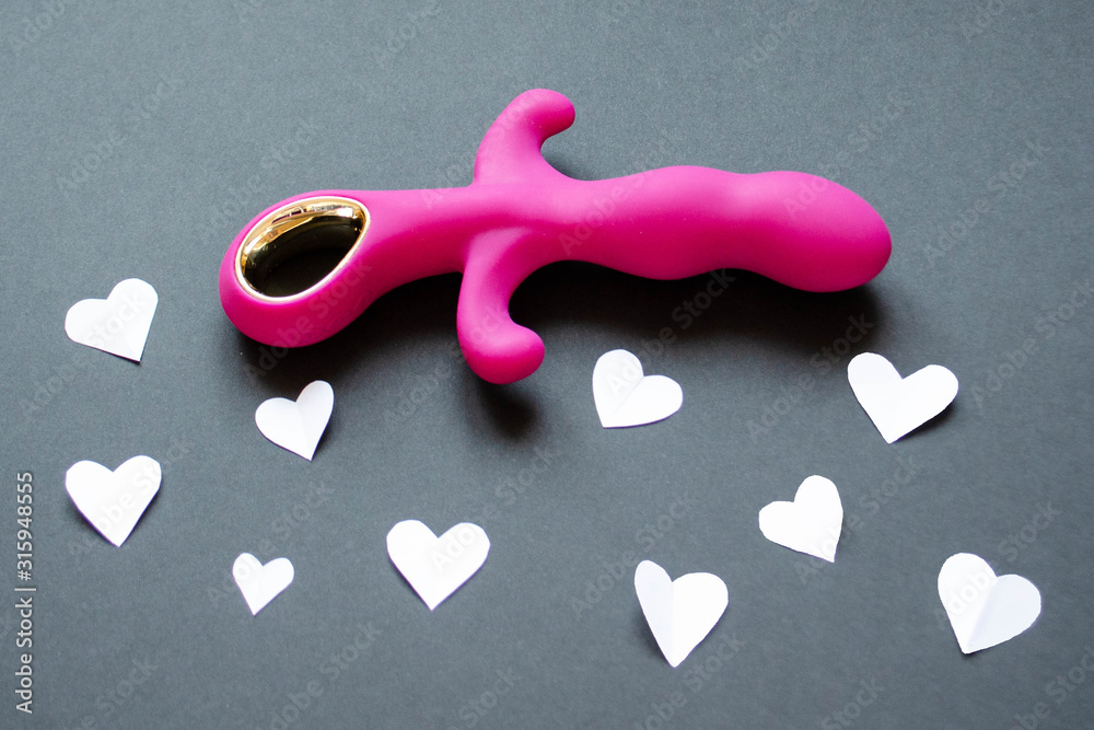 Obraz premium Sex toy. Pink vibrator on a black background with hearts. Useful for sex shop