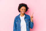 Young african american woman against a pink backgroound isolated showing victory sign and smiling broadly.