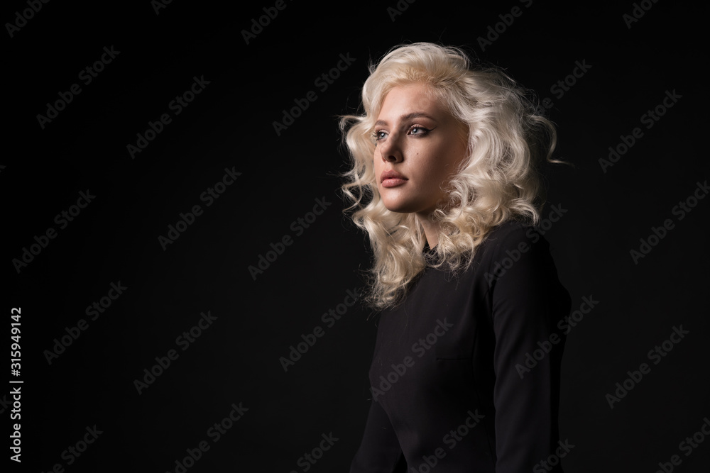 Beautiful woman with curly hairstyle looking away isolated on black background